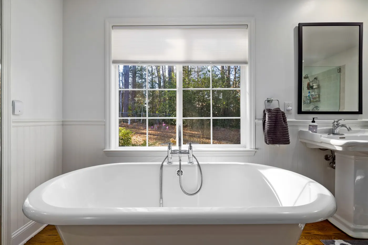 Bright bathroom with a freestanding white tub beneath a large window