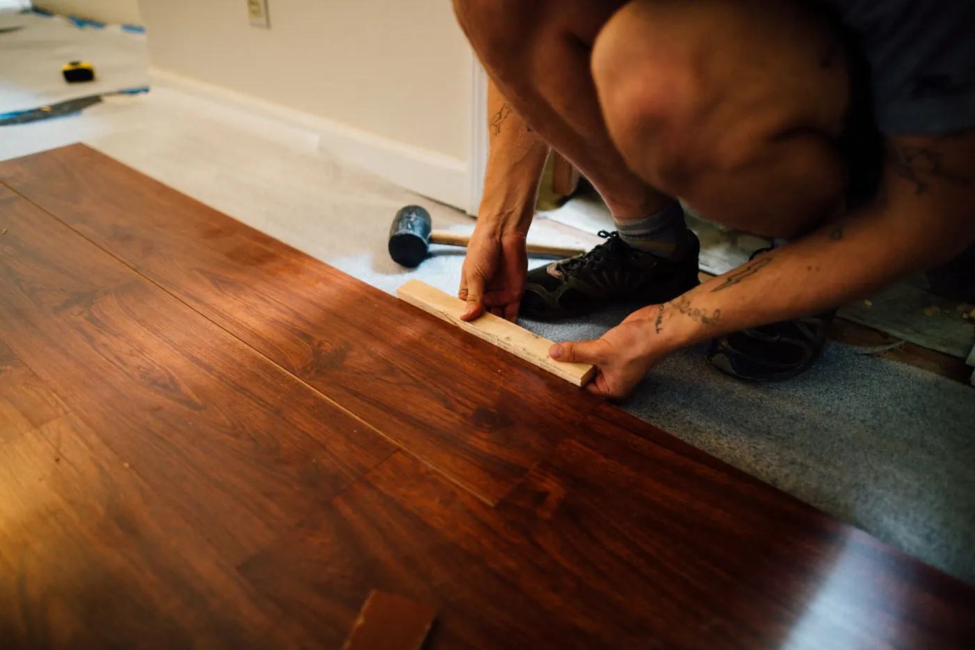 Installer tapping a wood-look laminate plank into place