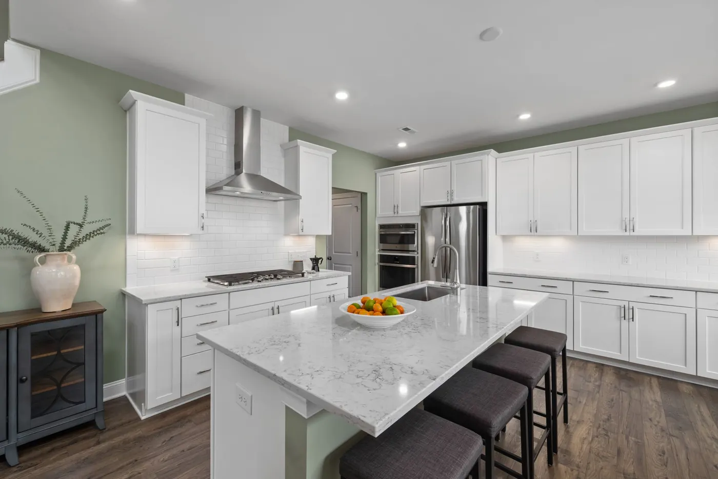 White kitchen with a large island, stone counters and stainless appliances