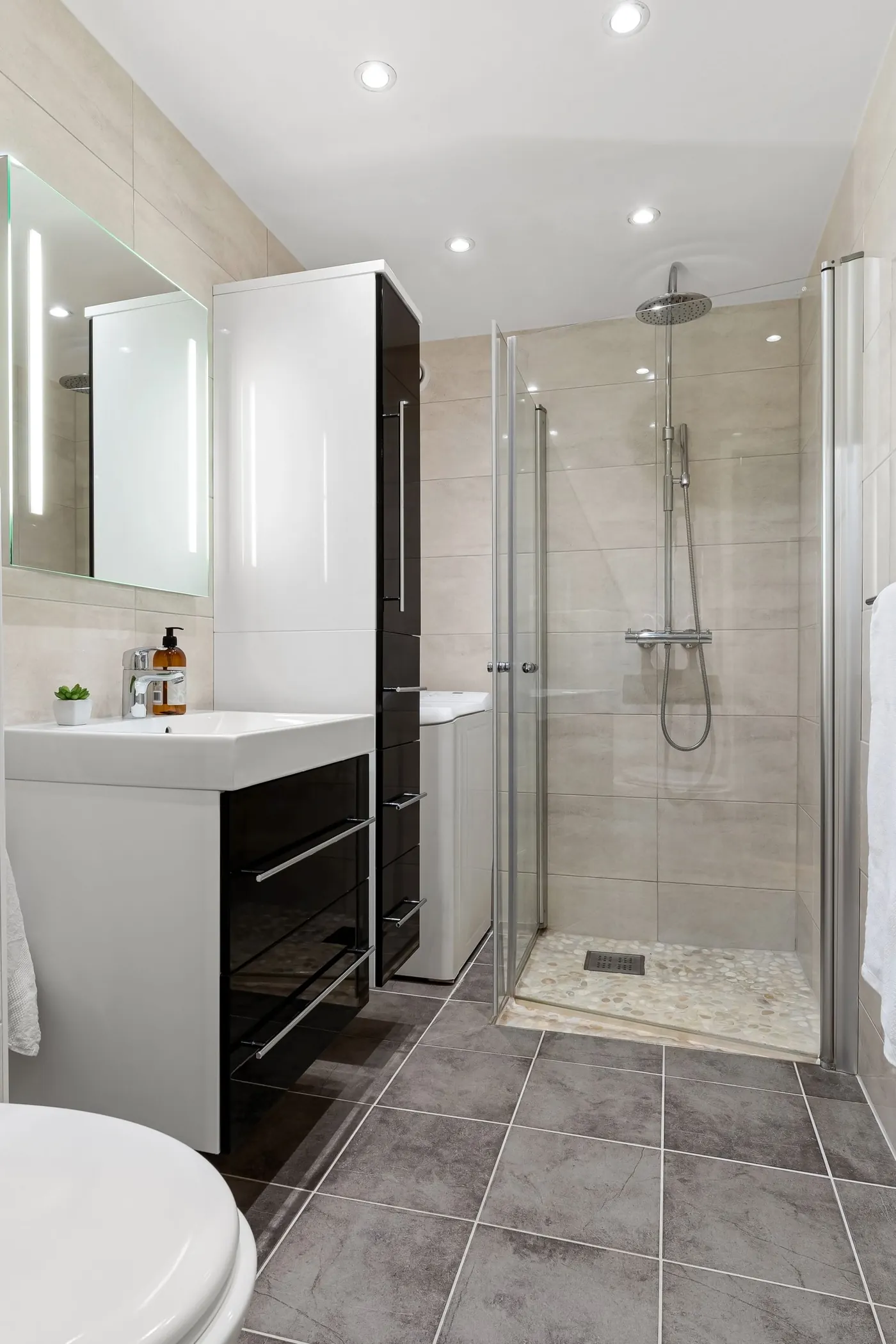 Glass-enclosed walk-in shower stall next to a dark wood vanity