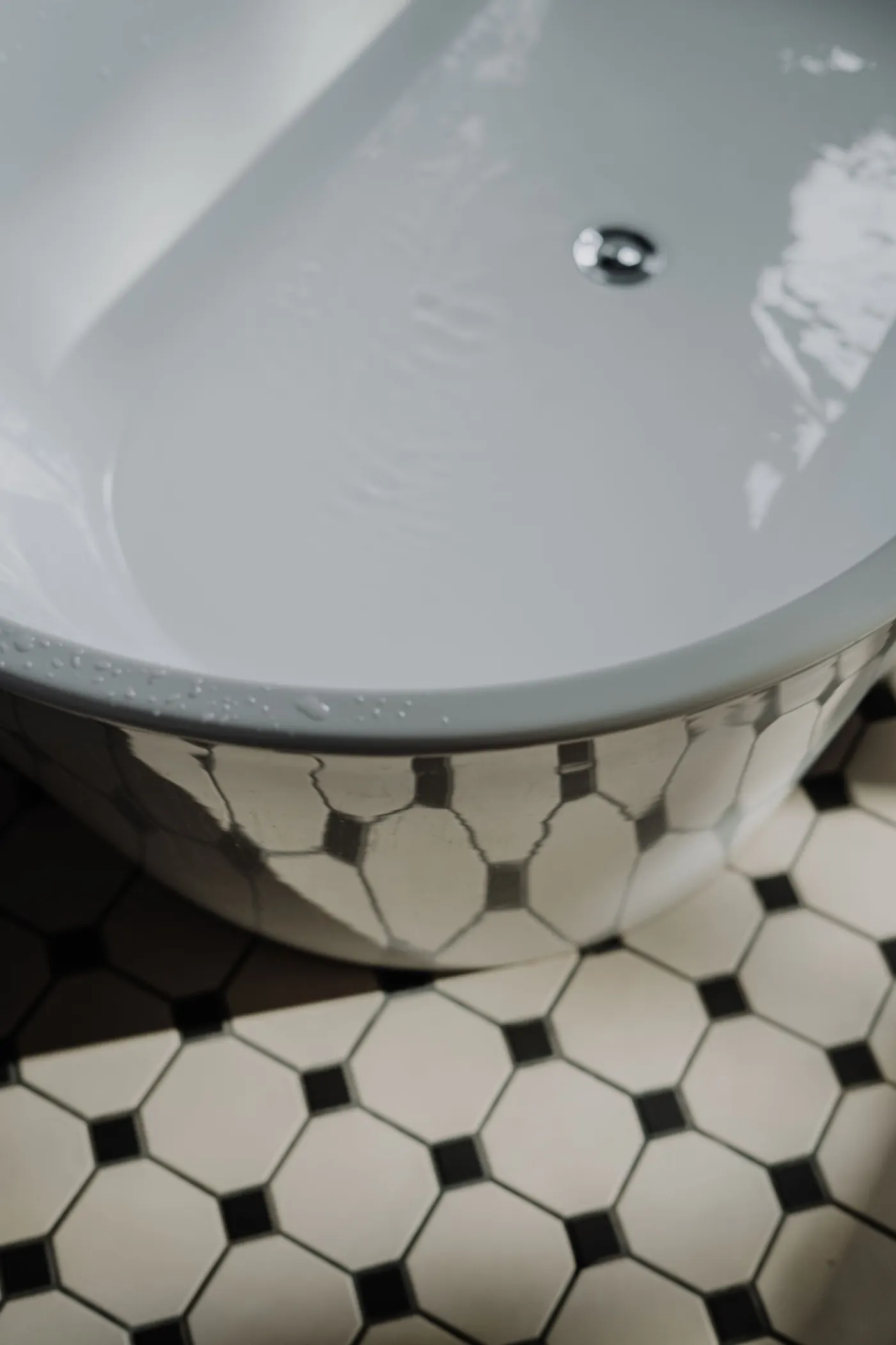 Close-up of black and white hexagon floor tile next to a white tub